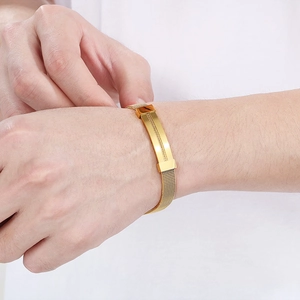 Detail of gold mesh stainless steel bracelet on wrist showing texture and flexibility
