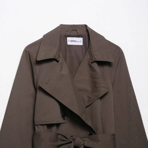 Kurzer brauner Damen Trenchcoat mit Reverskragen und Taillengürtel auf weißem Grund