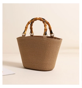Detail of natural woven straw bag featuring vintage bamboo top handles and striped texture