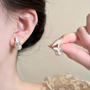 Detailed view of silver butterfly stud earrings with sparkling crystals and elegant white pearls