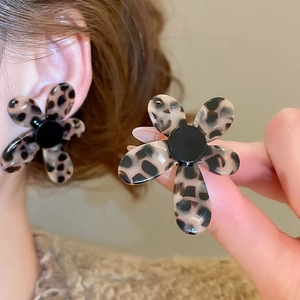 Detail of leopard print flower earrings crafted from acetate material on a model ear