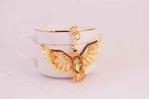 Macro detail of eagle keychain with amber crystals leaning on a ceramic cup