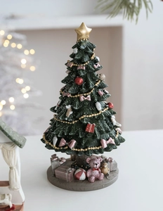 Detailed view of pink resin Christmas tree with gold stars and festive base ornaments