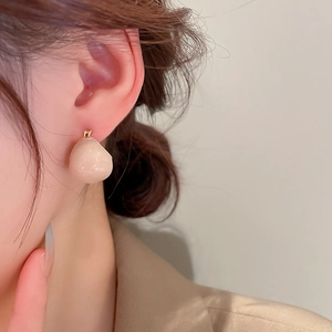 Macro detail of nude coffee teardrop earring on model with gold plated plating