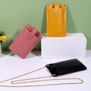 Detail of colorful mini woven phone bags in pink, yellow, and black with chain straps