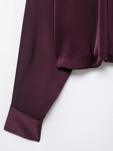 Detail view of smooth dark purple satin fabric cuffs and hem with silk texture