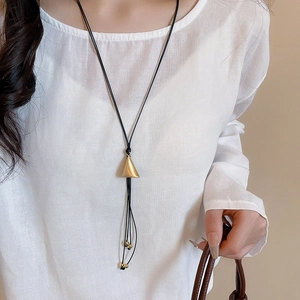 Detail of adjustable black leather necklace with golden triangular pendant and bead tassels