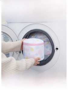 Placing a cylindrical mesh laundry bag with rabbit prints into a front-load washing machine