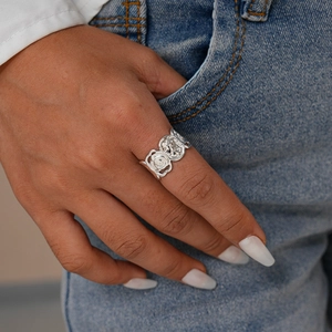 Vue détaillée d'une bague ours argentée portée à la main sur fond de jean en denim