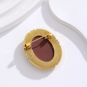 Back view of vintage golden alloy oval brooch with red-brown inlay and safety pin