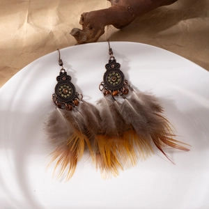 Macro detail of Bohemian feather earrings with beads on a ceramic plate background