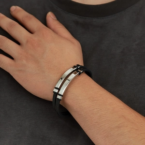 Close-up of a double-layer black rubber bracelet with silver metal plate on a male wrist