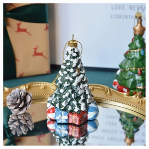 Detailed view of a green Christmas tree ornament with snow coating on a gold mirror tray