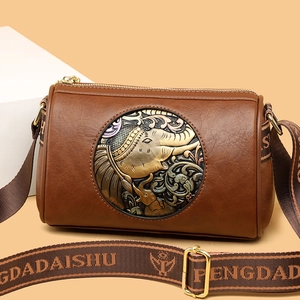 Brown leather cylinder shoulder bag with elephant metal badge and wide woven strap