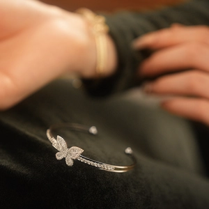 Macro side view of silver butterfly open bangle with sparkling cubic zirconia on green velvet