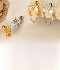 Detail of titanium steel stud earrings with bow and Ferris wheel charms in gold and silver