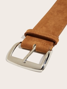 Detail of a brown suede wide waist belt featuring a shiny silver metal buckle and neat stitching