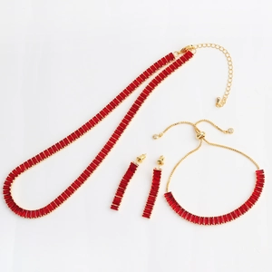 Macro detail of red rectangular gemstones and gold base on necklace, bracelet and earrings