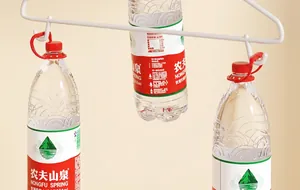 Dettaglio di un appendino in metallo bianco che sostiene tre bottiglie d'acqua per la portata