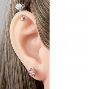 Detail of titanium steel seashell ear studs with pink zircon and blue shell charms