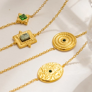 Detailed close-up of four vintage 18K gold-plated bracelets with emerald green gemstones