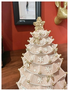 Macro detail of a pink layered Christmas tree music box with gold bows and pearls