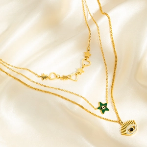 Détail de colliers dorés à plusieurs rangs avec œil porte-bonheur et étoiles sur soie