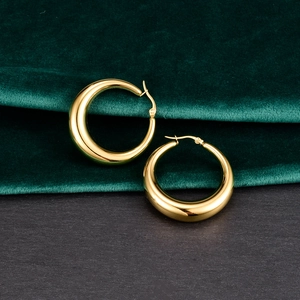 Detalle de los pendientes de aro gruesos bañados en oro de 18K sobre terciopelo verde