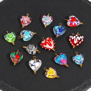 Macro view of assorted colorful heart-shaped glass charms with metallic gold jump rings