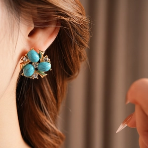 Détail de puce d'oreille vintage en or avec pierres turquoises et zircons sur l'oreille