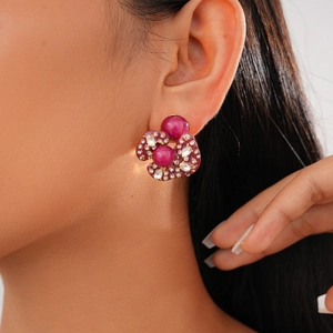 Close-up of a floral geometric stud earring with purple gems and zircon stones on a model