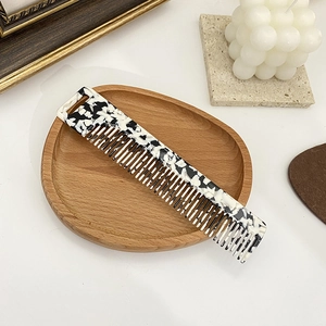 Macro view of wide-tooth tortoiseshell acetate hair comb on a wooden tray with a hanging hole