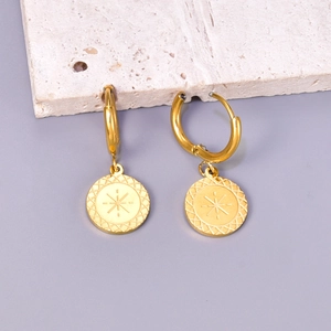 Golden titanium steel hoop earrings featuring engraved starburst coin pendants on marble