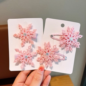 Detailed view of pink snowflake hair clips set for girls on a wooden background