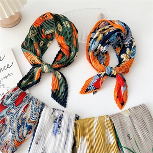 Variety of pleated square silk scarves with floral patterns displayed on a white background