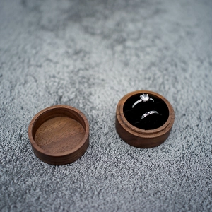 Detail view of the round black walnut wood ring box with soft velvet lining and rings