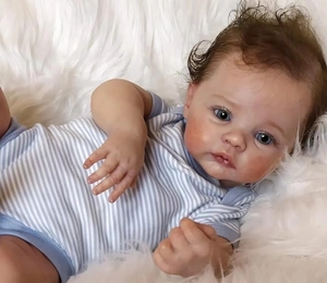 Close-up of lifelike Meadow baby doll with detailed 3D skin and blue eyes in stripe romper