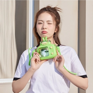 Detail of creative TV-shaped light green straw cup with bunny ears and crossbody strap