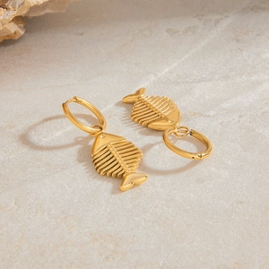 Detail shot of vintage gold fishbone drop earrings on a natural grey stone background