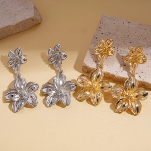 Elegant gold and silver metallic double flower earrings on light stone pedestal