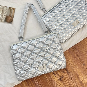 Close-up of silver quilted tablet sleeve with metallic finish and fabric brand label
