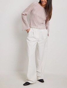 Detail of elegant pleated pink top with flare sleeves and high waist white trousers