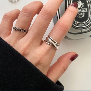 Close-up of layered 925 sterling silver woven ring and vintage textured band