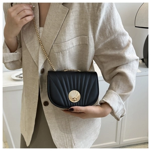 Detail of black leather saddle bag featuring a gold shell clasp and quilted embroidery
