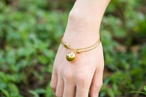 Gros plan d'un bracelet doré double couche avec des pendentifs sphériques au poignet