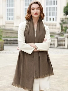 Detail view of brown cashmere-like scarf with soft fringes worn elegantly by a model