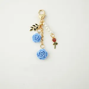 Detail of rose and pearl keychain with heart-shaped clasp and gold-plated metal leaves
