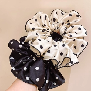 Elegant polka dot satin hair scrunchies in black and cream colors worn on wrist