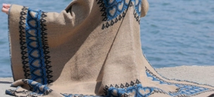 Poncho à capuche ethnique aux motifs géométriques noirs et bleus porté au bord de mer