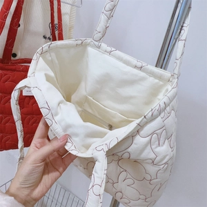 Detailed interior of a white quilted tote bag featuring inner pockets and a zipper closure